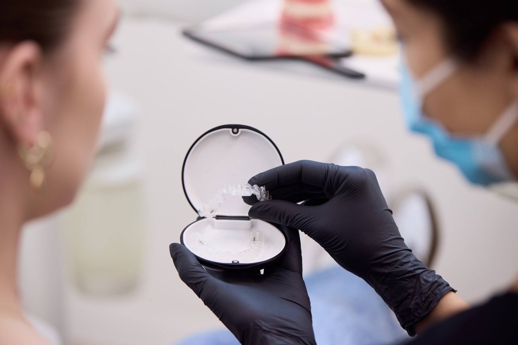 A clinician showing an unbranded clear aligner tray during a consultation